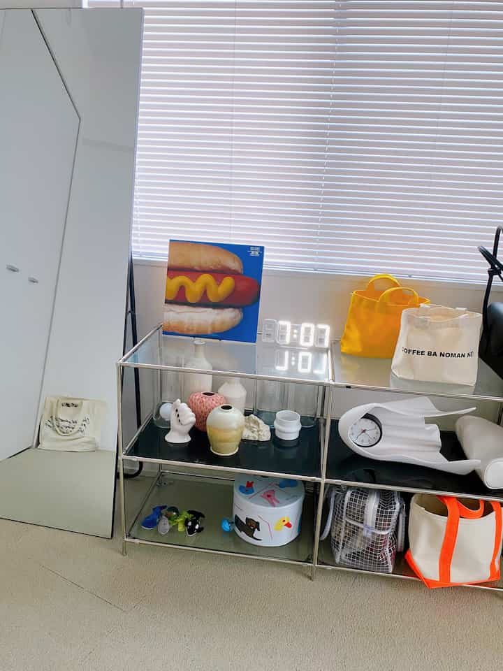A simple modern storage space featuring a white closet and beige carpet with metal rack organizing various items