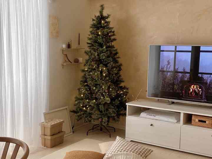 白とナチュラルの色調のリビング、中央にライトが灯るクリスマスツリーが配置された雰囲気のあるインテリア