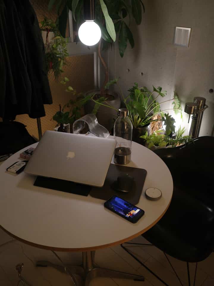 White-toned round room featuring a round table, floor lamp, and plants in a modern workspace