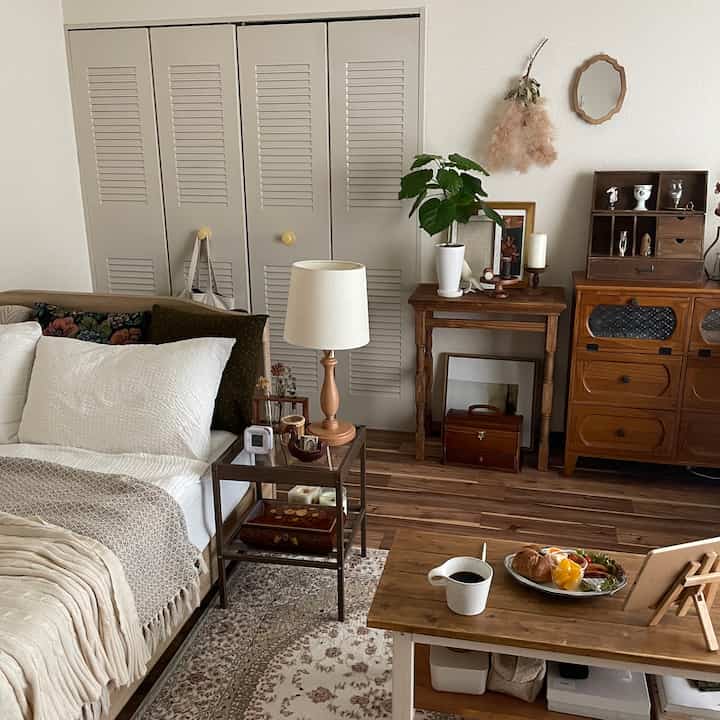 Cozy bedroom with brown wood tones and white bedding, featuring a nightstand and table lamp in a natural modern style space
