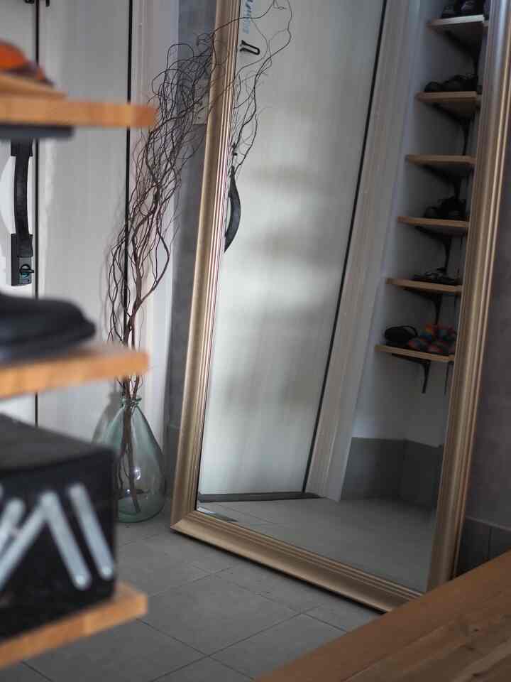 Natural wood tones and a transparent glass vase accompany a large clear mirror in a simple entrance area