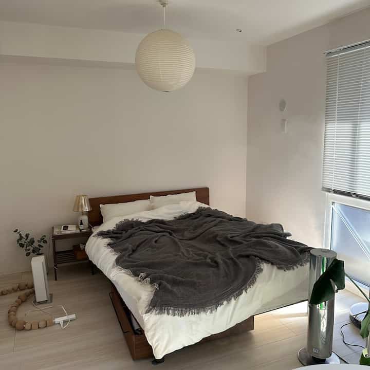 白と茶色のナチュラルカラーが調和したホテルライクな寝室、快適なベッドとサイドテーブルが配置された落ち着いた空間