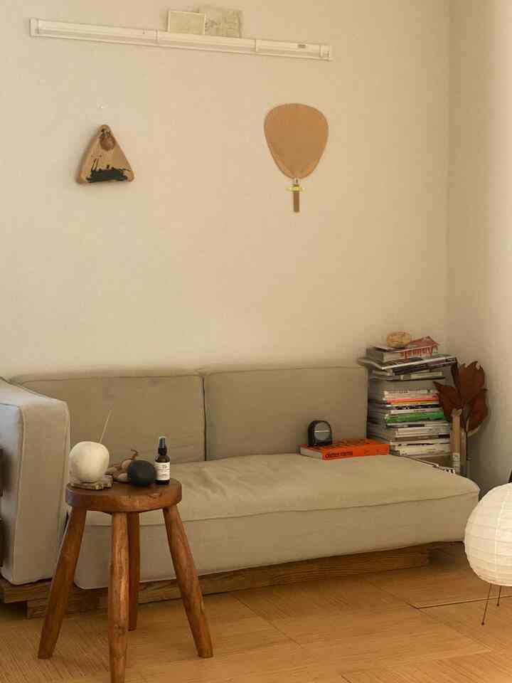 Natural tone living room in beige and wood, featuring a simple sofa and a round wooden stool with minimalistic design