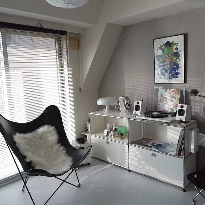 グレーと黒のトーンのリビング、バタフライチェアとホワイトのサイドボードが配置されたモダンでインダストリアルな印象的な空間