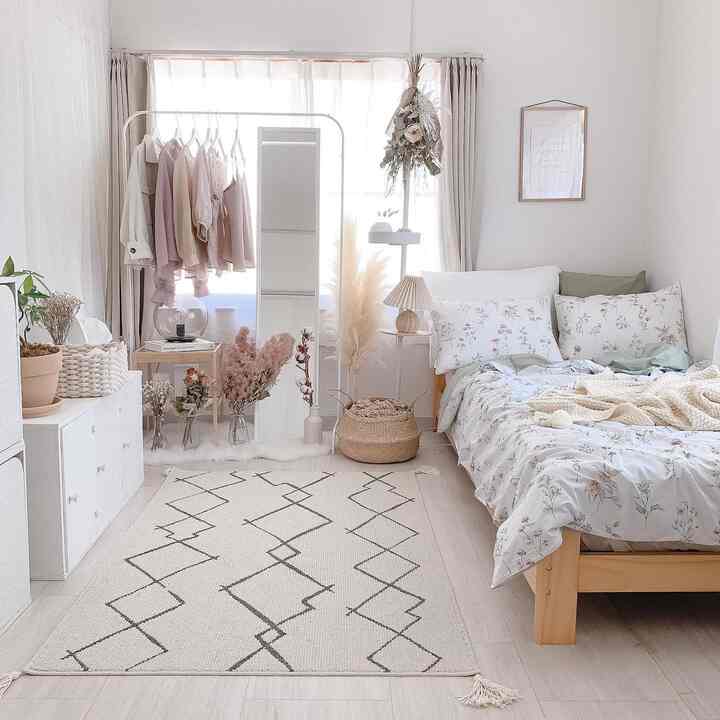 白とベージュのトーンの寝室、中央に全身鏡と木製ベッドフレームが配置され、自然素材の小物が温かみのある雰囲気のインテリア