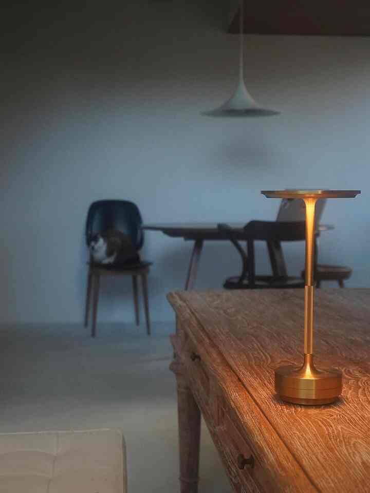 Modern dining room with gold-toned table lamp on vintage wooden table, featuring a warm and simple atmosphere
