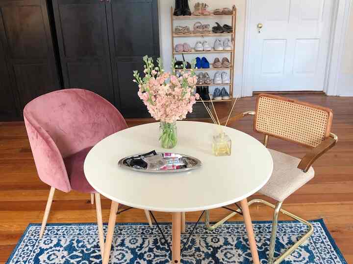 White and wood tone dining room featuring a round dining table, chairs, and a vase with flowers creating a cozy atmosphere