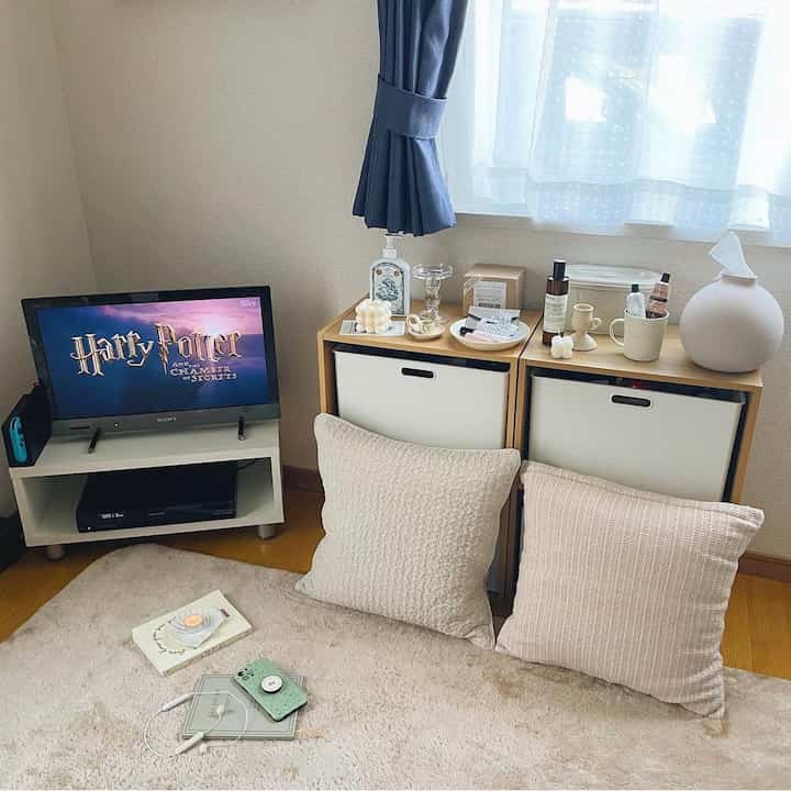 白と茶色のトーンでまとめられた狭くシンプルな部屋、テレビ台と収納棚が配置された韓国インテリアの雰囲気ある空間