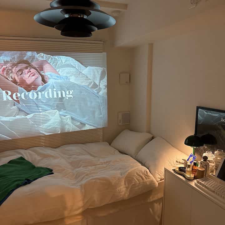 白を基調とした寝室、ブラインドにプロジェクター映像が映し出された温かみのある印象的な空間