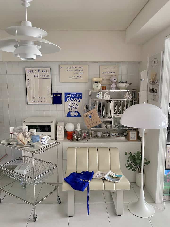 白と青の色調のダイニングルーム、モジュール家具のトロリーとペンダントライト、クリーム色のベンチが配置されたモダンで清潔感のあるインテリア