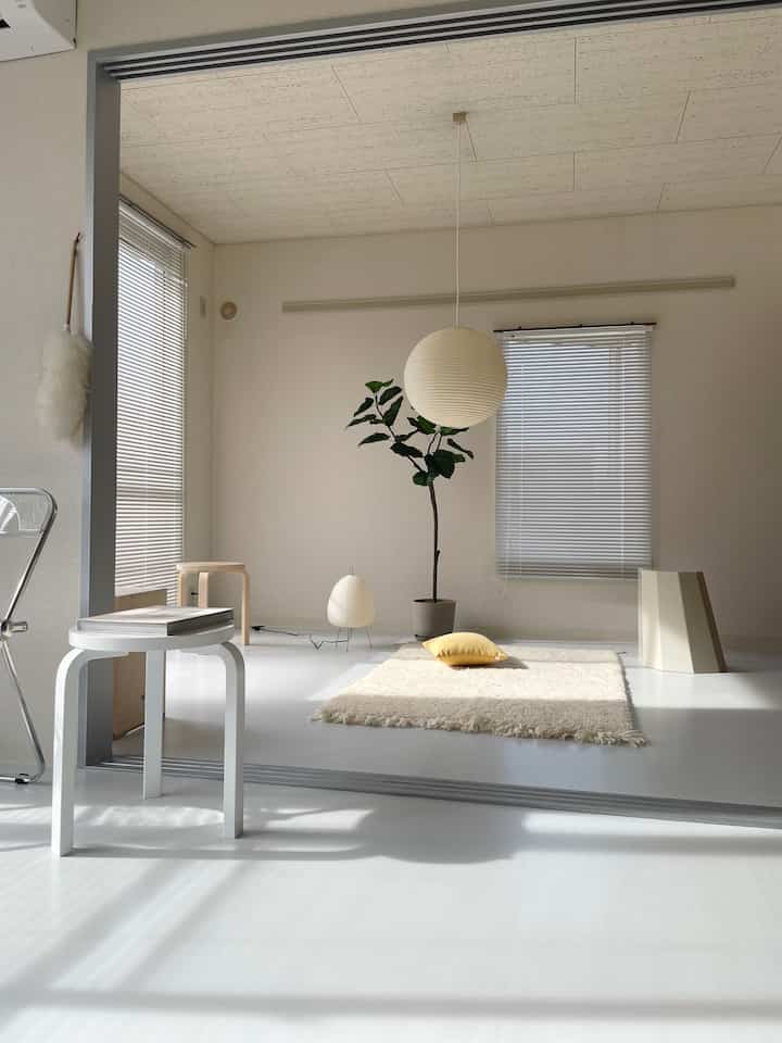 Bright white and beige toned minimal studio apartment with natural light and a leafy plant creating a calm atmosphere