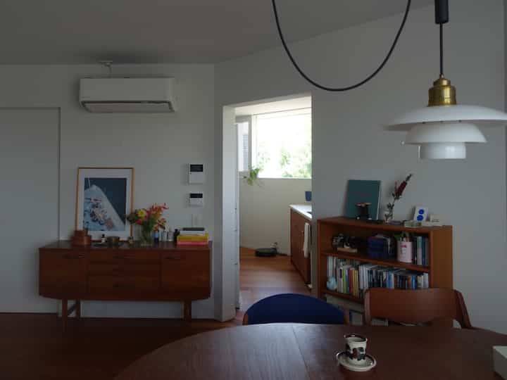 白い壁と木目調の家具が配置されたダイニング、ペンダントライトが印象的な空間