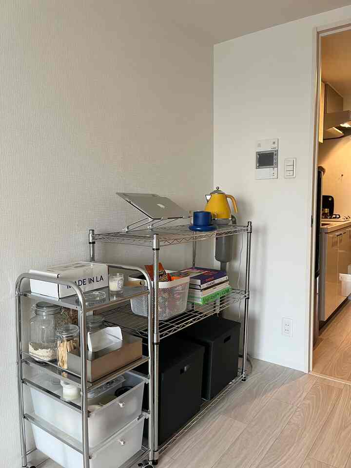 Minimalist space next to kitchen featuring white walls and silver storage shelves