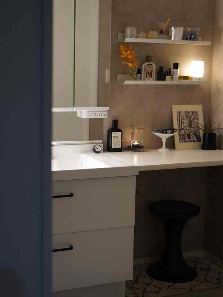 白とナチュラルカラーのパウダールーム、白い家具と黒いスツールが配置された落ち着いた雰囲気のインテリア