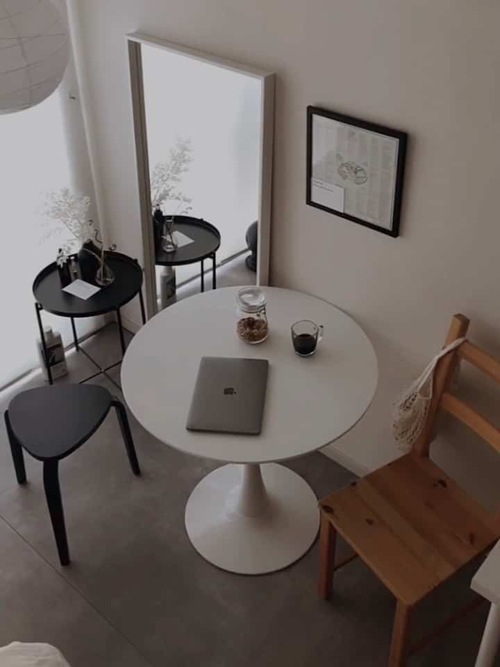 Compact dining area in white and black tones featuring a round table and wooden chair with a natural, simple feel