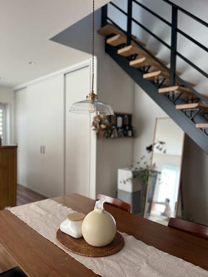 A warm wood tone dining room featuring a transparent pendant light and placemat on the table in a neat natural setting