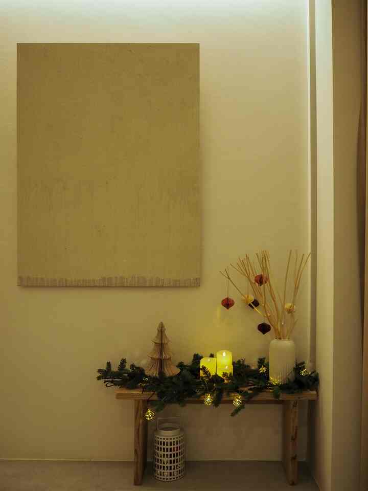 Beige-toned entrance space featuring an old wooden bench decorated with seasonal ornaments and LED candles, creating a simple and natural atmosphere