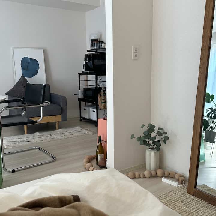 Natural toned bedroom corner featuring wooden frame mirror and plant with cozy atmosphere