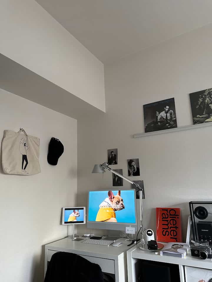 White and gray toned studio apartment home office featuring a desk, computer, and bookshelf in a simple modern setup