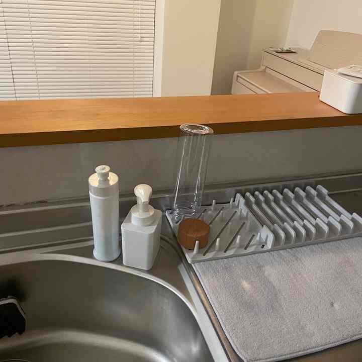 ホワイトと木目調が調和したキッチンの洗面台周り、整然とした食器乾燥ラックと小物が配置された雰囲気のあるインテリア