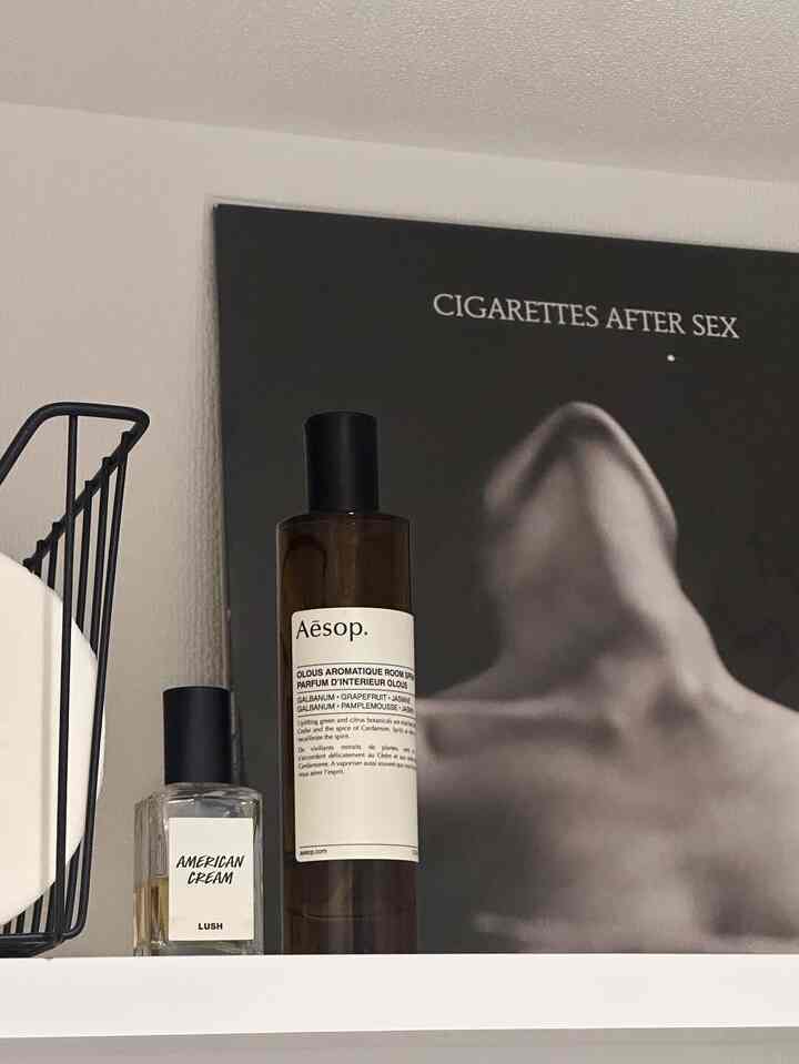 白い壁に黒い背景のポスターとアロマティックルームスプレーが置かれたモダンでトレンディなトイレのインテリア