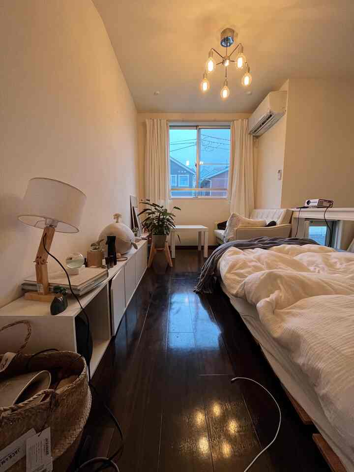 ダークブラウンの床と白い家具が配されたモダンな一人暮らしの寝室のインテリア