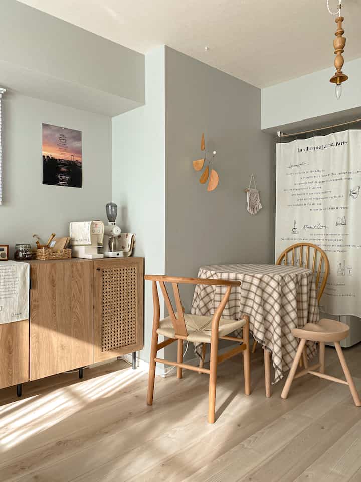 Natural wood-tone compact dining room featuring wooden furniture and a checkered tablecloth creating a simple atmosphere