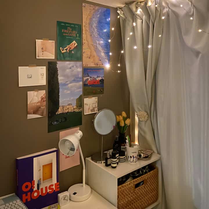 暖かいブラウンの壁と白いカーテン、化粧台の鏡とストリングライトが配置された雰囲気のある小さな寝室のインテリア