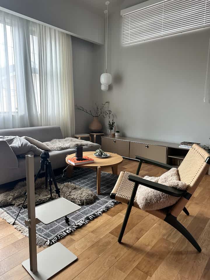 ナチュラルな色調のリビング、グレーのソファと木のコーヒーテーブル、アームチェアが配置されたモダンでミニマルなインテリア