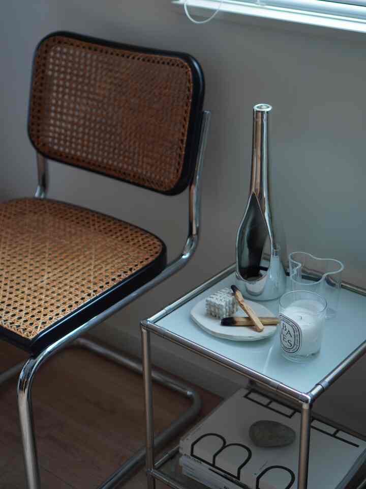 A modern living area by the window featuring a wood-tone Cesca chair and a silver modular nightstand