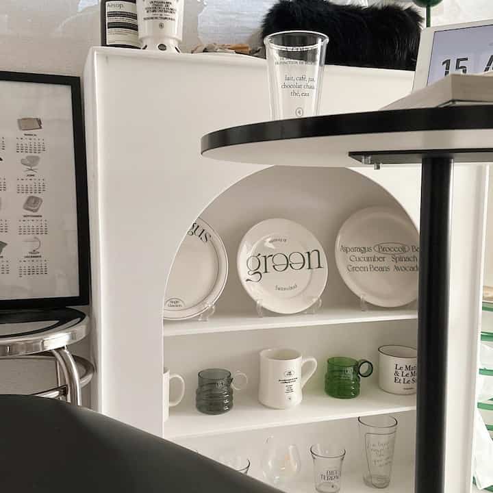 ホワイトとグリーンの色調のリビング、韓国風の皿が飾られたマントルピースのある印象的な空間