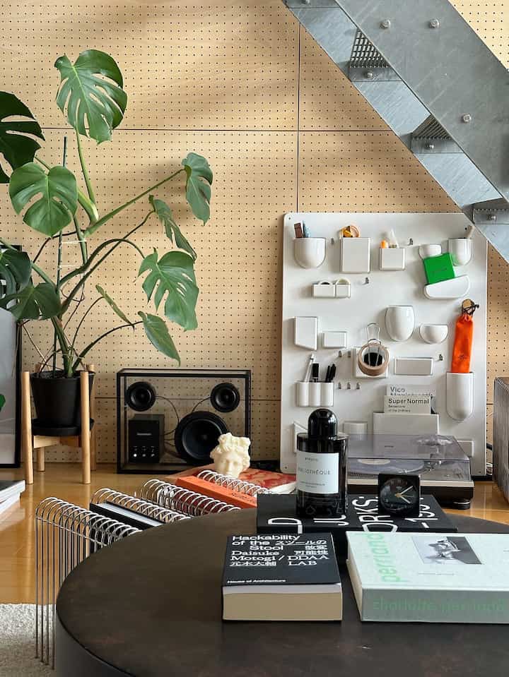 ナチュラルな色調のリビング、モダンな家具と壁掛け収納、大きな植物と木の床が配置された雰囲気のあるインテリア