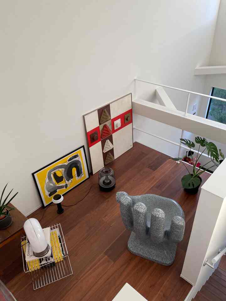 Natural wood tone loft with white walls featuring modern sculptural objet and framed abstract art creating an artistic cozy atmosphere