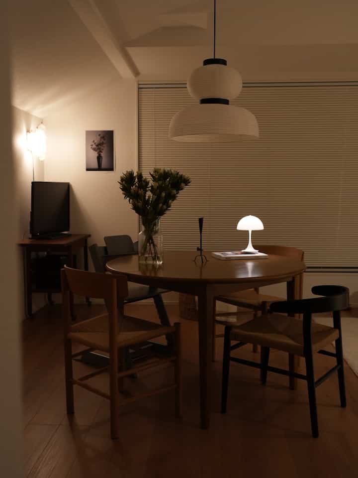 A quiet dining room with natural wood tones and soft lighting, featuring a round dining table and chairs