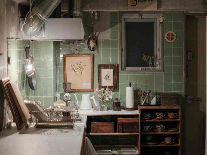 緑色のタイル壁と木製棚が配置されたナチュラルな雰囲気の温かみのあるキッチン。