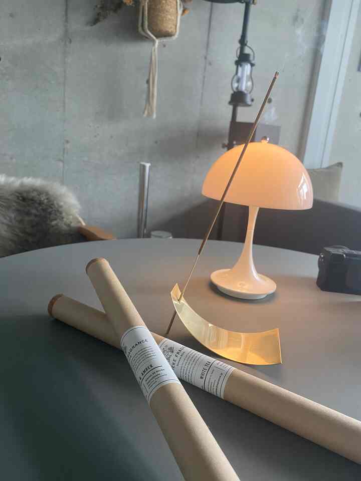 ブラウンとゴールドのトーンが際立つモダンなインテリアで、テーブルに置かれたお香スティックとスタンドのある落ち着いたリラックス空間