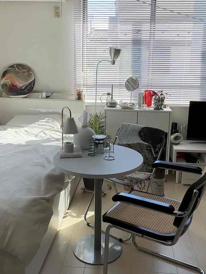 Bright white and silver-toned modern studio bedroom featuring a neatly arranged table and chairs
