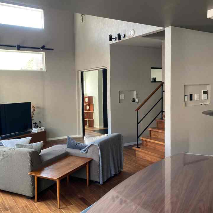 グレーと木目調が調和した8畳のリビング、低めのソファとテレビ台が配置されたナチュラルモダンな空間