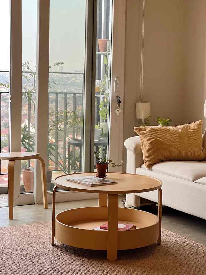 Beige and wood-tone living room featuring a round coffee table, sofa, and balcony creating a cozy atmosphere