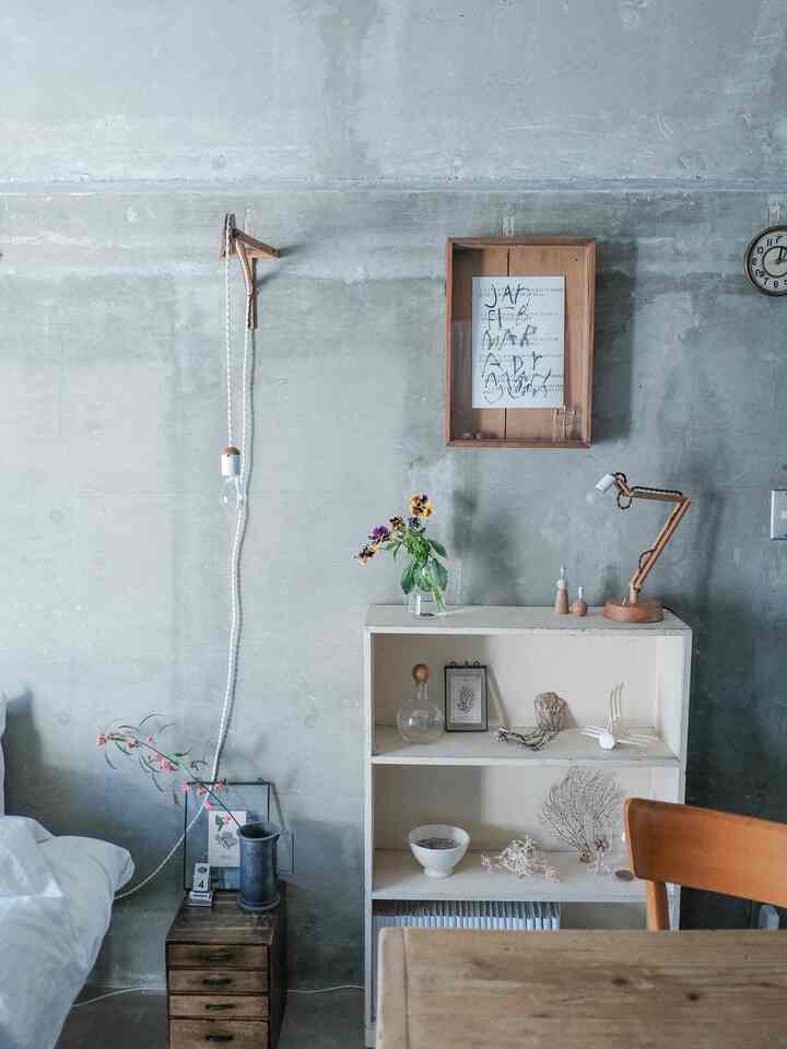 ナチュラルなトーンのワンルーム、コンクリート壁と木目調家具が配置されたミニマルな雰囲気のインテリア