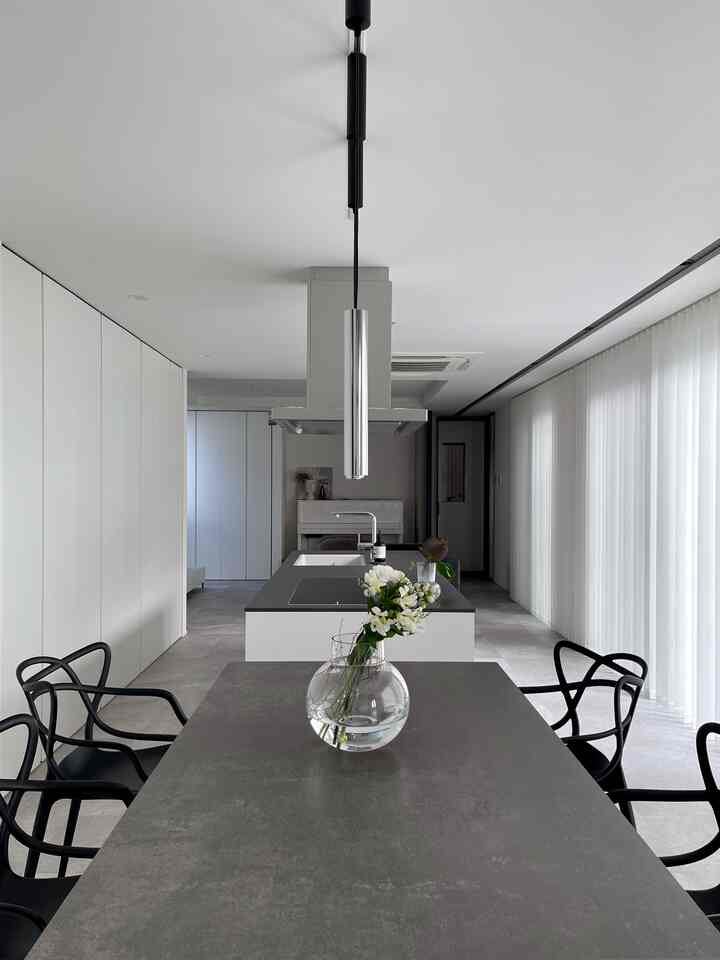 白と黒のトーンのダイニング、ダイニングテーブルに透明な花瓶が配置され、洗練されたモダンな雰囲気の空間