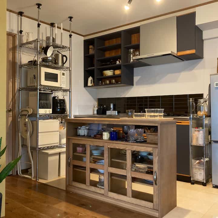 Natural tone kitchen featuring a wooden kitchen island and open storage cabinets with clean modern design