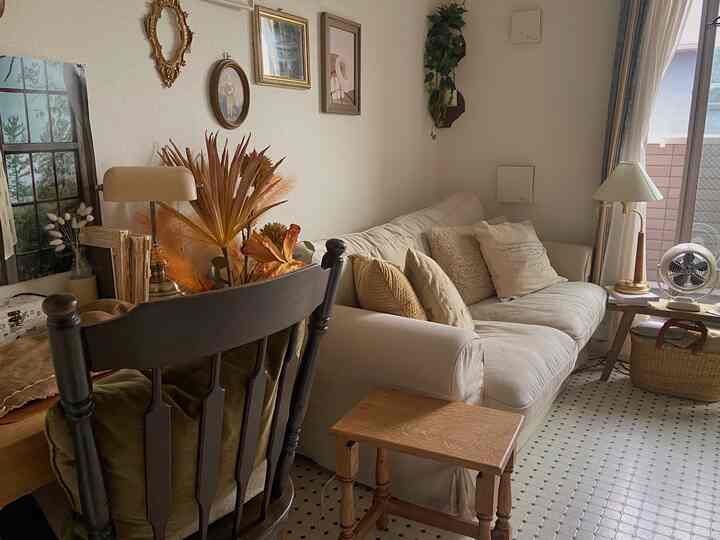 ベージュとホワイトの色調のリビング、ゆったりとしたソファとサイドテーブル、自然の植物が配置された雰囲気のあるインテリア