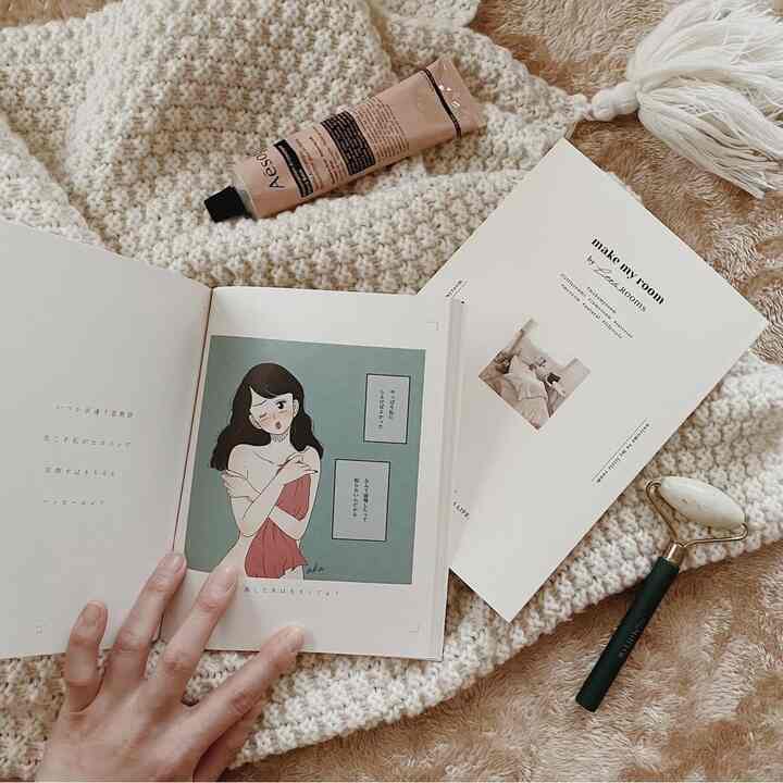 ベージュ調の小さな部屋、柔らかいニットブランケットの上に本とマッサージローラーが置かれた落ち着いた読書空間