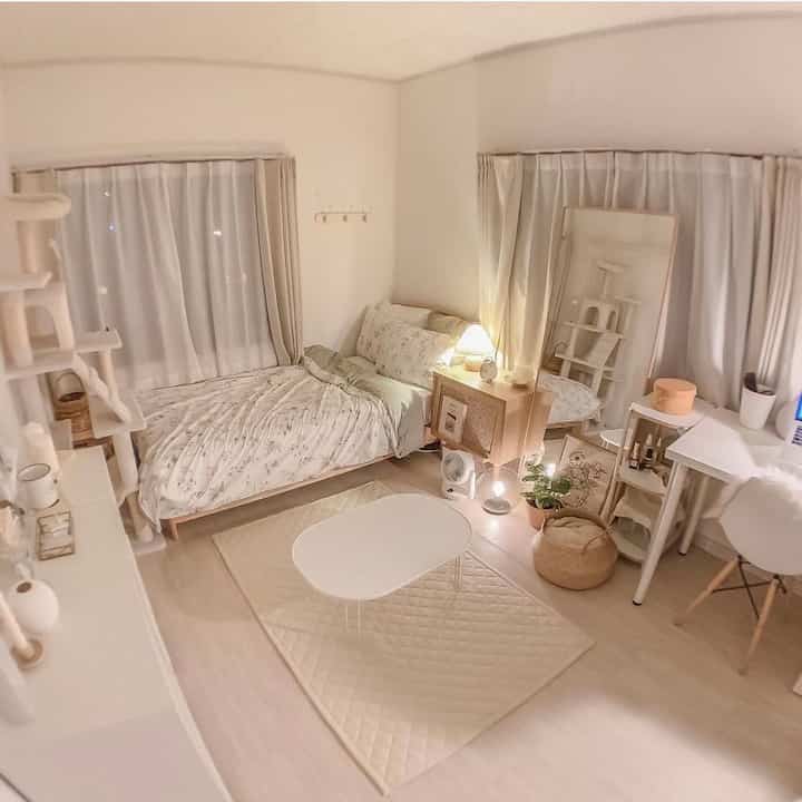 A soft pastel-toned 4.5-tatami bedroom featuring a simple bed, rug, and a cat tower for pets, creating a cozy atmosphere