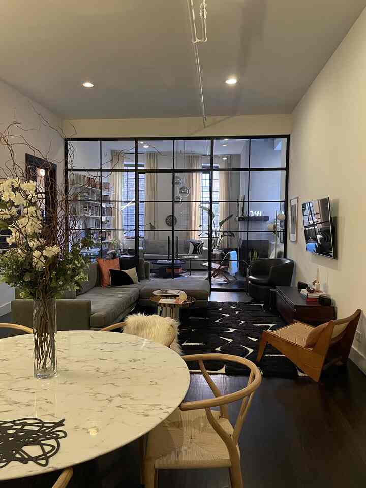 Natural tones dining area and modern living room with black rug and sofa