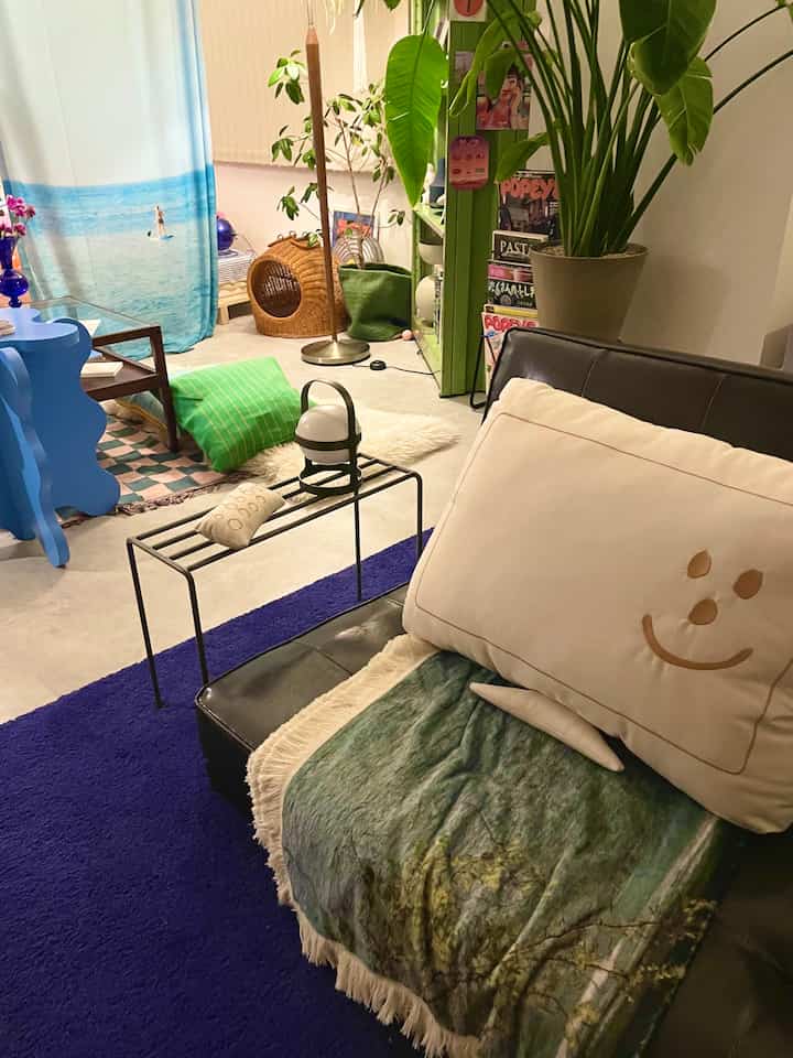 ブルーとグリーンの調和が取れた居心地の良いリビング、ヴィンテージソファと植物、サイドテーブルが配置された印象的な空間