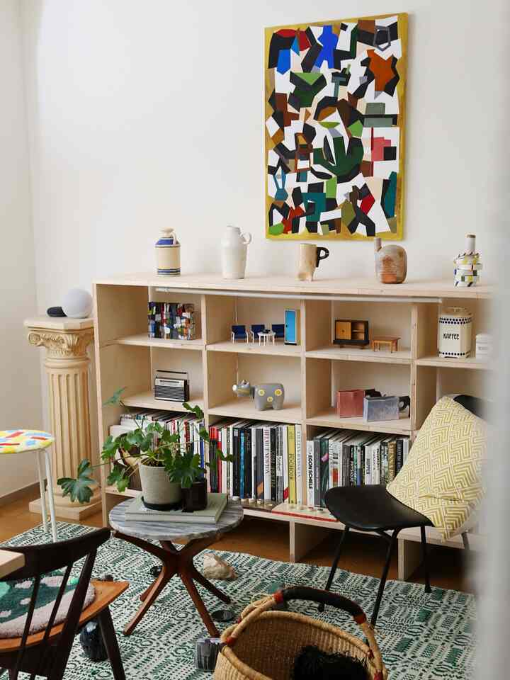 ナチュラルな木目調と白い壁のリビング、書棚と多彩なデザイン雑貨が配置された雰囲気のある空間