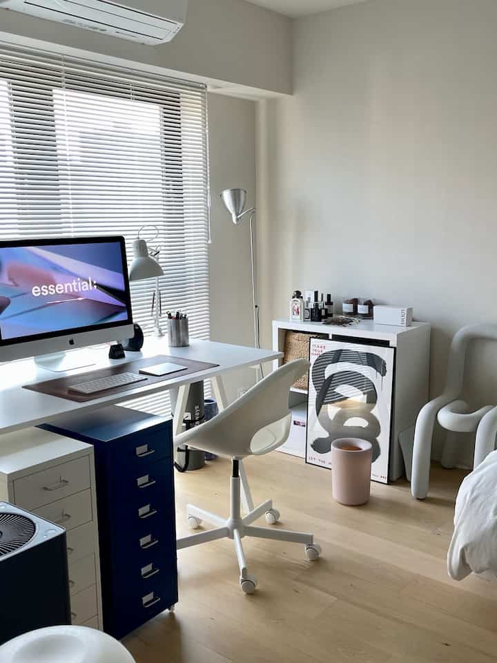 白とナチュラルカラーのワンルームのホームオフィス、デスクとオフィスチェアが配置されたシンプルで落ち着いた雰囲気のインテリア