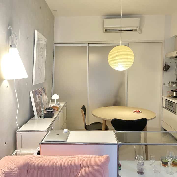 白とベージュのモダンなダイニングキッチン、丸いダイニングテーブルとペンダントライトが配置された雰囲気のある空間